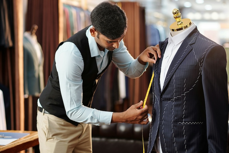 A man altering a suit on a mannequin - Learn why custom tailoring is better than off-the-rack with Pearce Bespoke  