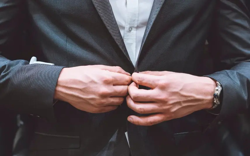 A close up shot of a person in a stylish, dark Pearce Bespoke tailored suit.