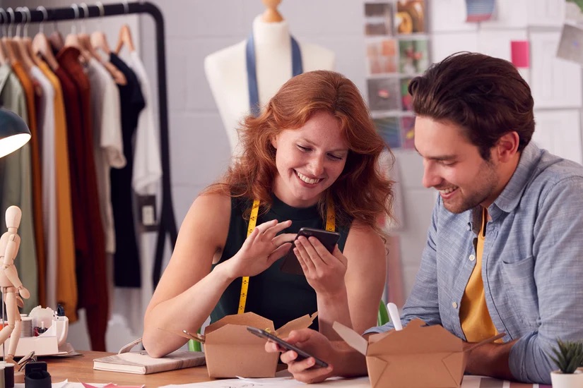 A man and woman looking at their phones - Expanding Your Franchise Network: Key Factors for Successful Pearce Bespoke Franchise Growth