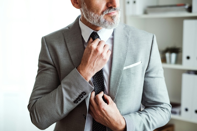 A man tightening his tie on his bespoke suit from Pearce Bespoke.