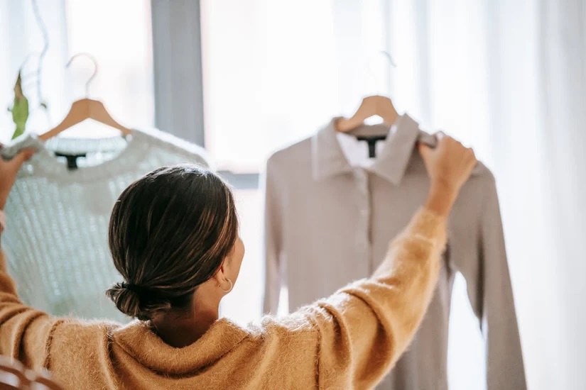 A woman holding up two quality shirts made by Pearce Bespoke. 
