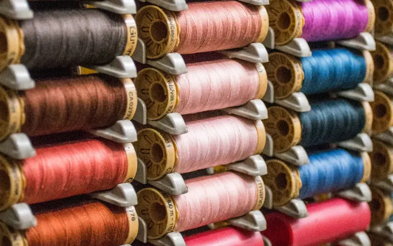 Racks filled with spools of different colored thread - learn more about finding the perfect franchise fit for you with Pearce Bespoke.