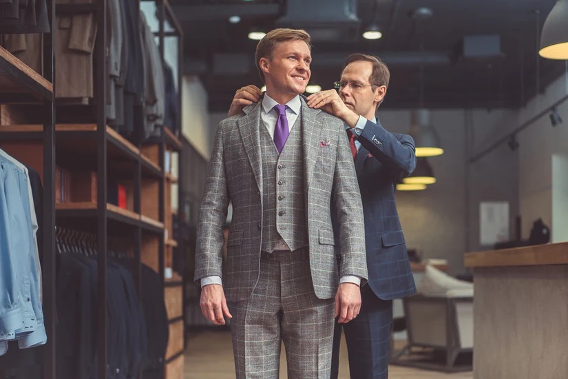 A man in a blue suit altering a suit for a client - Unleashing Success in Luxury Tailoring with Our Pearce Bespoke Franchise