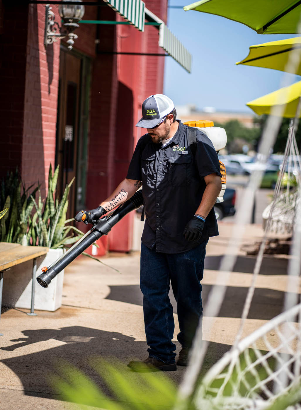 A GGA Pest Management technician working on a red business building, contact us today for commercial pest control in Waco, TX.