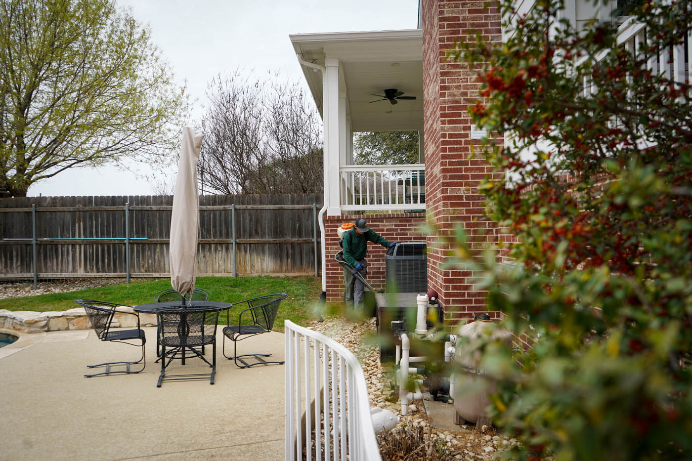 A GGA Pest Management technician working on pest control in Hillsboro, TX on house bushes.