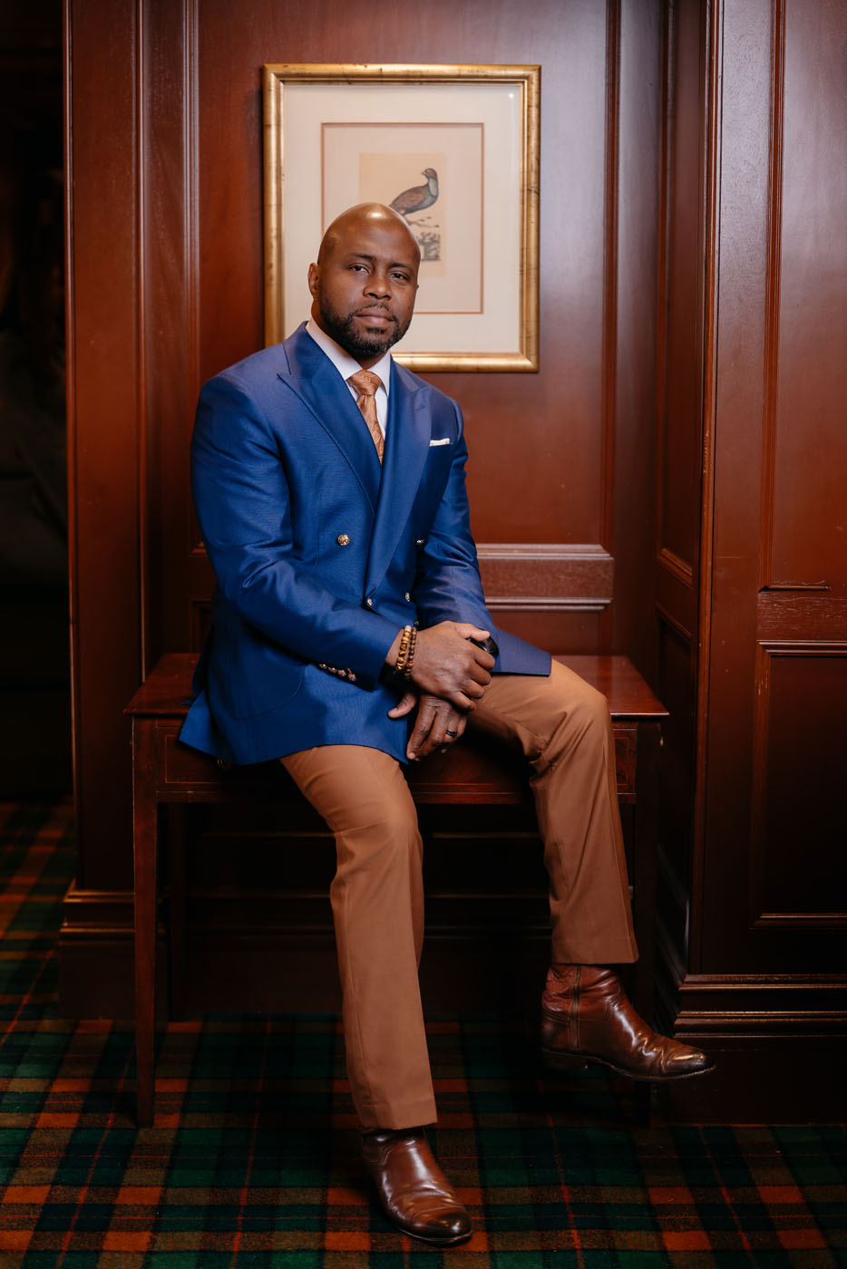 A man wearing a custom blue suit jacket and brown trousers from Pearce Bespoke.